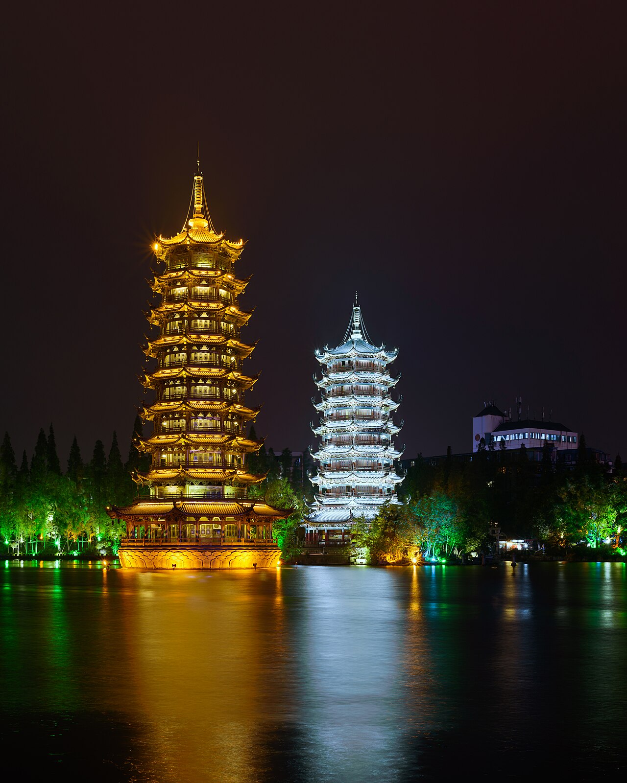 Sun and Moon Twin Towers illuminated at night on Shanhu Lake in Guilin
